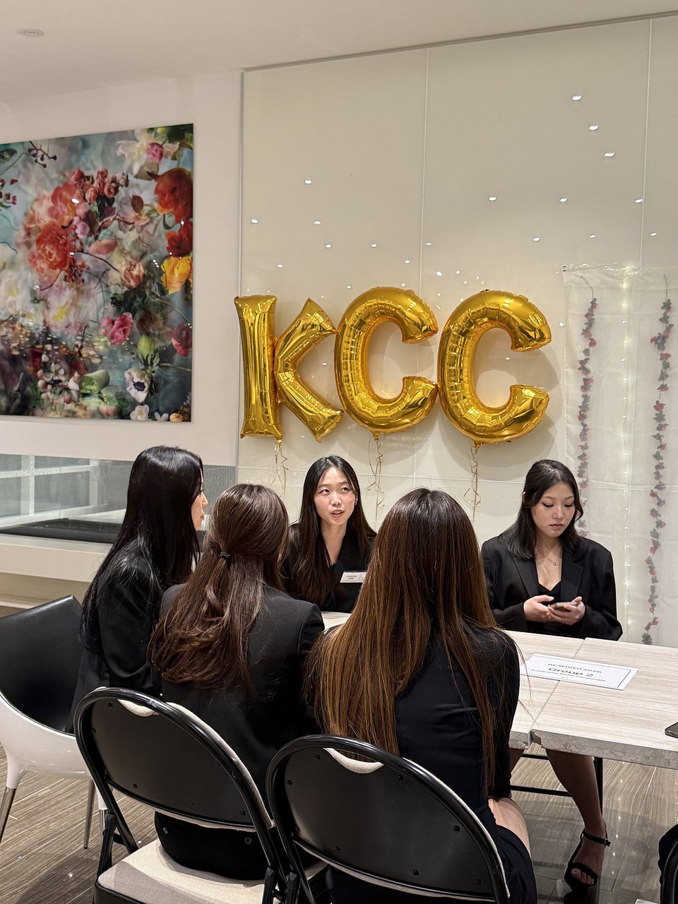 Members chatting in front of gold KCC balloons
