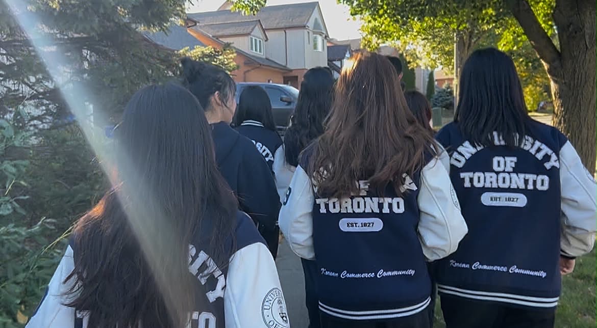 Members in varsity jackets in the afternoon sun
